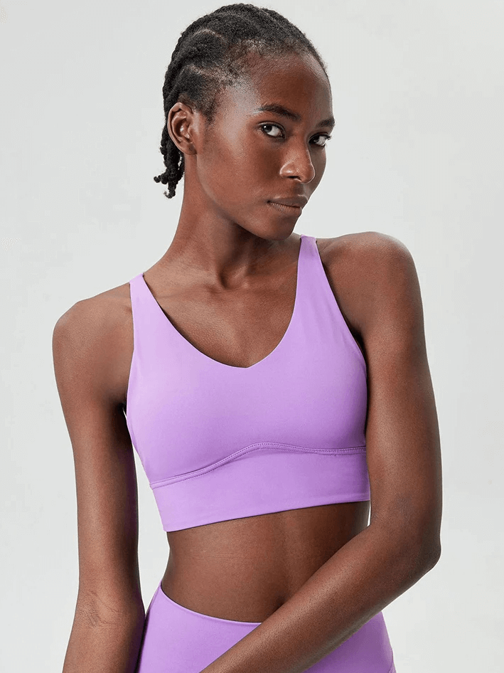 Woman wearing vibrant violet sports bra with a chic design and supportive straps, perfect for workouts.